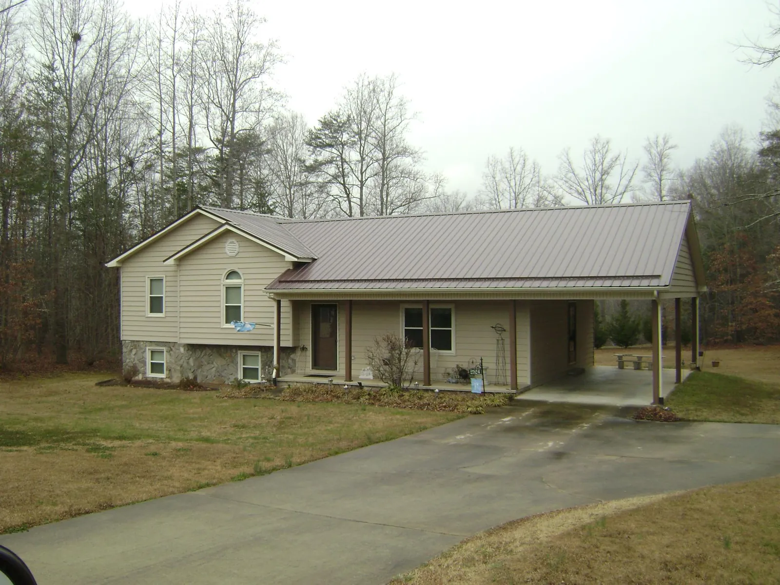 Brown metal roof on a tan split level home with an attached carport in Gray